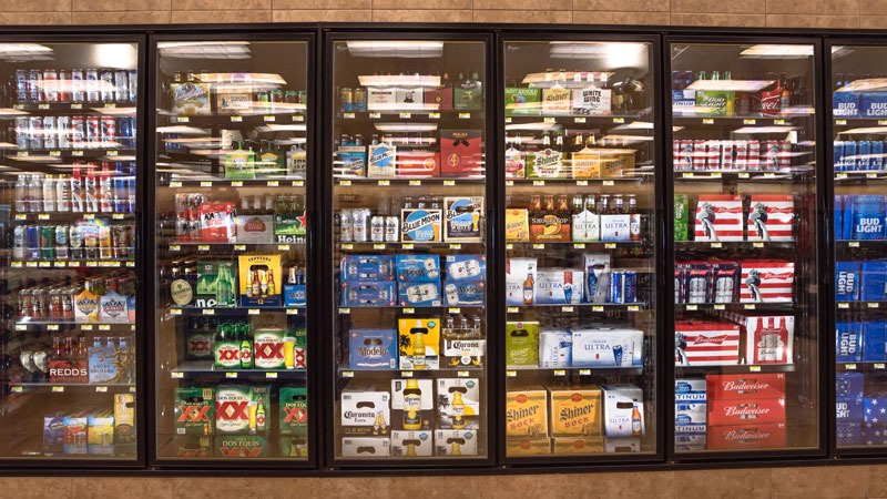 a grocery store cooler stocked with beer of various sizes