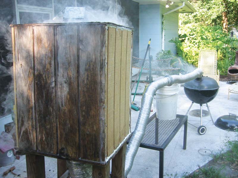 charcoal grill with a long exhaust vent to a smoking box where malt is cold-smoked for flavor